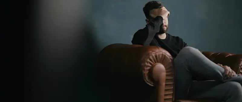 hombre con dolor de cabeza en el sofa